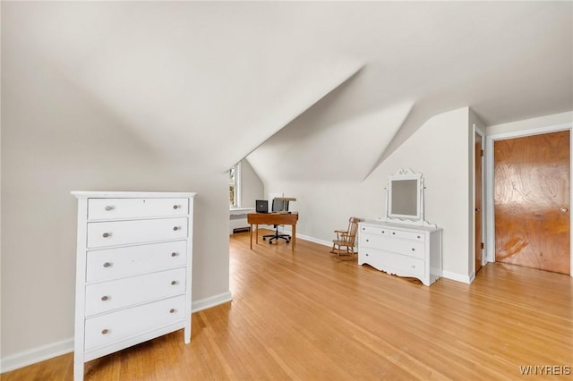 interior space with baseboards, vaulted ceiling, and light wood-type flooring