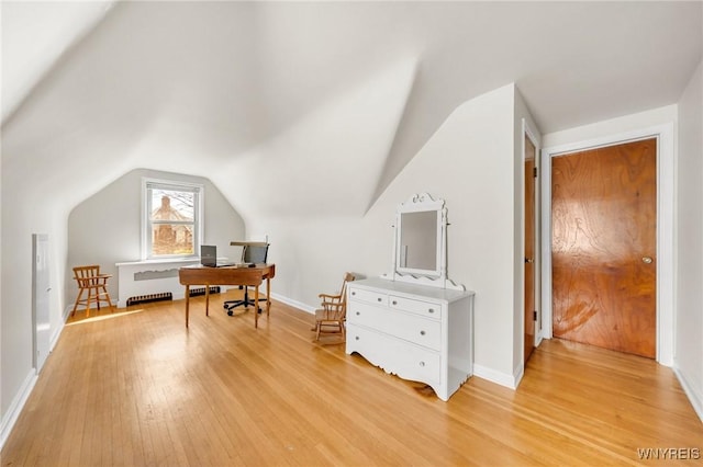 office space with light wood-type flooring, baseboards, and vaulted ceiling