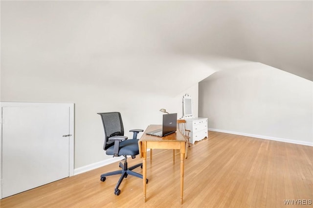 office area featuring light wood-style floors, baseboards, and vaulted ceiling