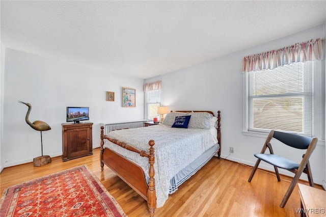 bedroom with light wood-type flooring, baseboards, and radiator