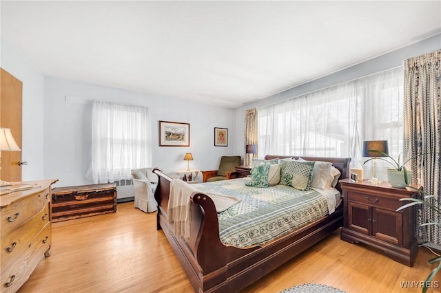 bedroom featuring radiator heating unit and light wood-style flooring