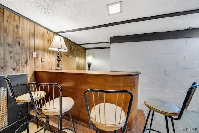 bar with concrete block wall, a bar, a textured ceiling, and visible vents