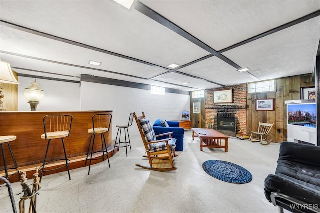 living area with wooden walls, concrete block wall, a fireplace, and a bar