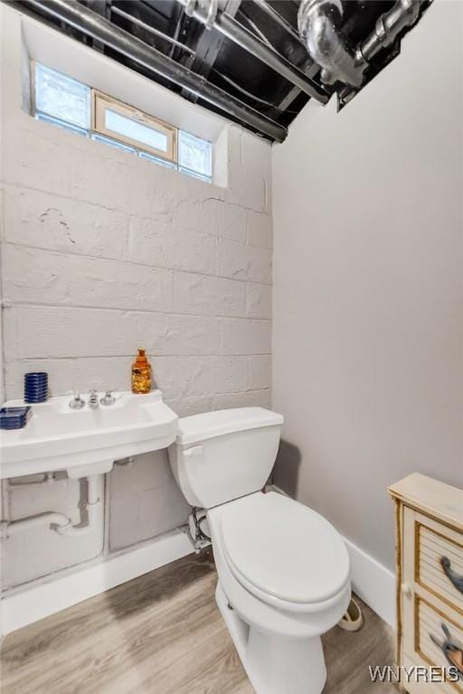 half bath with toilet, a sink, plenty of natural light, and wood finished floors