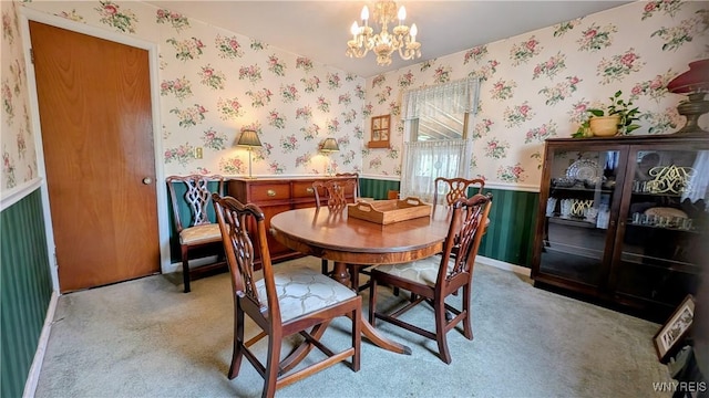 dining space with a wainscoted wall, a chandelier, light carpet, and wallpapered walls