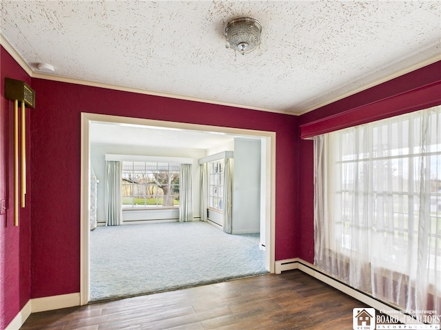 spare room featuring crown molding, baseboards, a baseboard heating unit, and wood finished floors