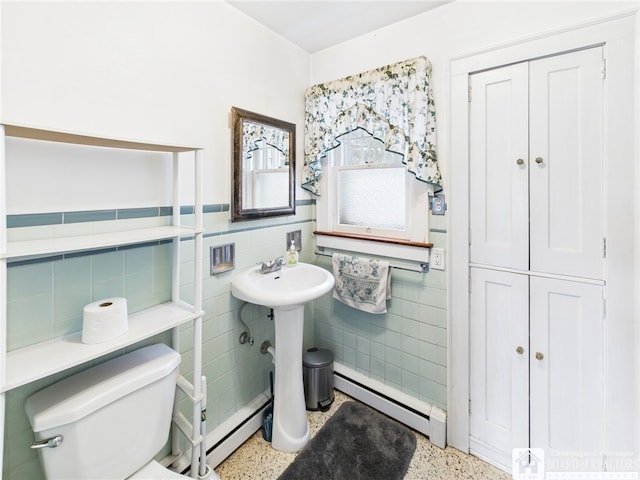 bathroom with a baseboard radiator, speckled floor, toilet, and tile walls