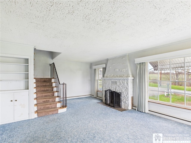 unfurnished living room with stairway, a textured ceiling, a fireplace with flush hearth, and carpet