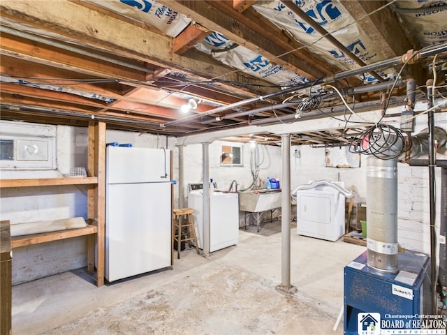 unfinished below grade area featuring freestanding refrigerator, washing machine and dryer, and a sink