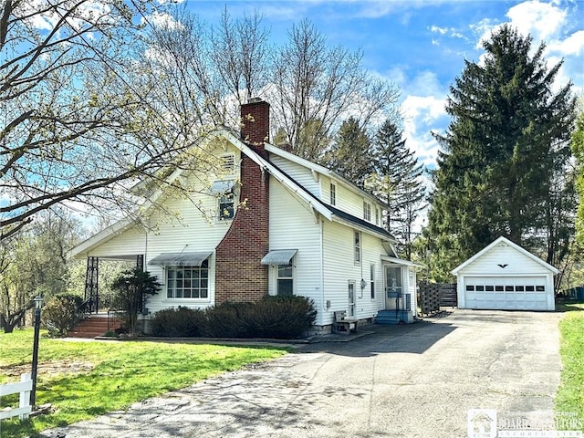 view of side of home with a chimney, a lawn, a garage, an outdoor structure, and entry steps