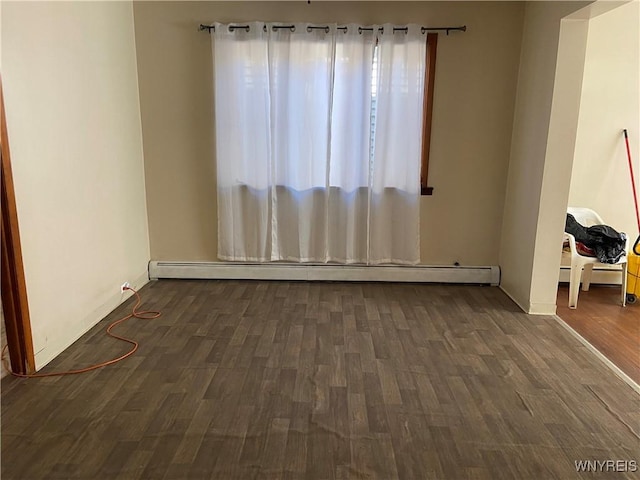 empty room with wood finished floors and a baseboard radiator
