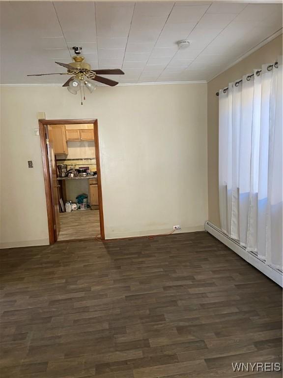 spare room featuring a ceiling fan, dark wood-style floors, ornamental molding, and a baseboard heating unit