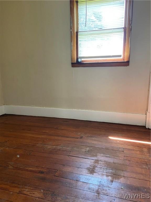 empty room with baseboards and dark wood-type flooring