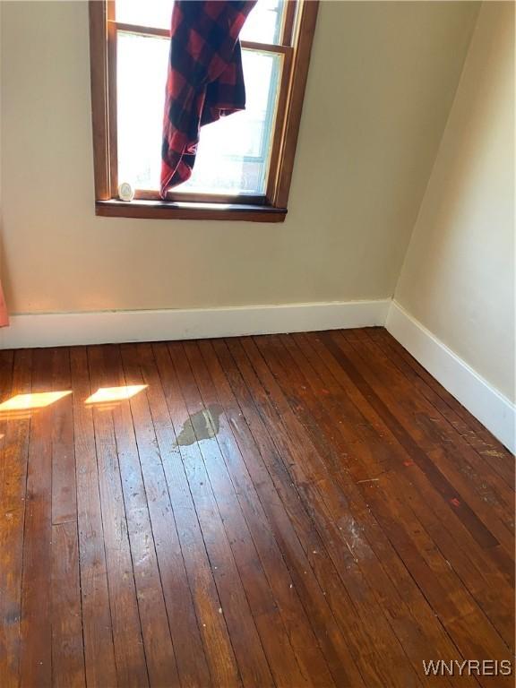 spare room featuring baseboards and hardwood / wood-style floors