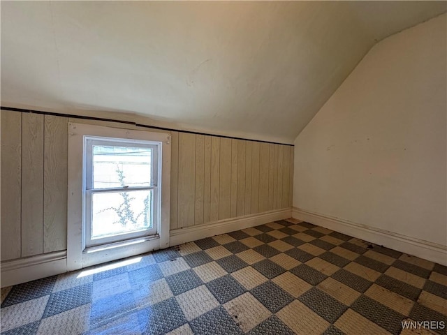 bonus room featuring baseboards, wood walls, and vaulted ceiling