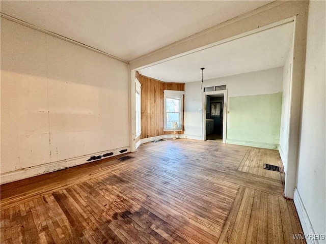 unfurnished living room with baseboards, a baseboard heating unit, hardwood / wood-style floors, and visible vents