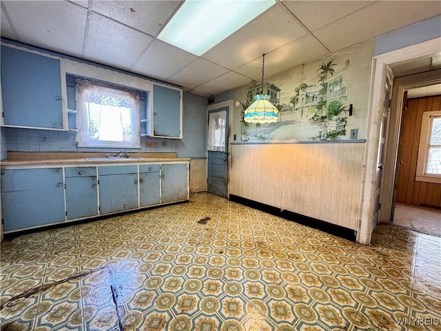 kitchen with tile patterned floors, a sink, a drop ceiling, and a wealth of natural light