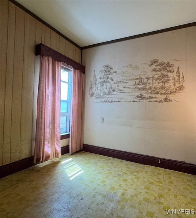 empty room featuring wooden walls and crown molding