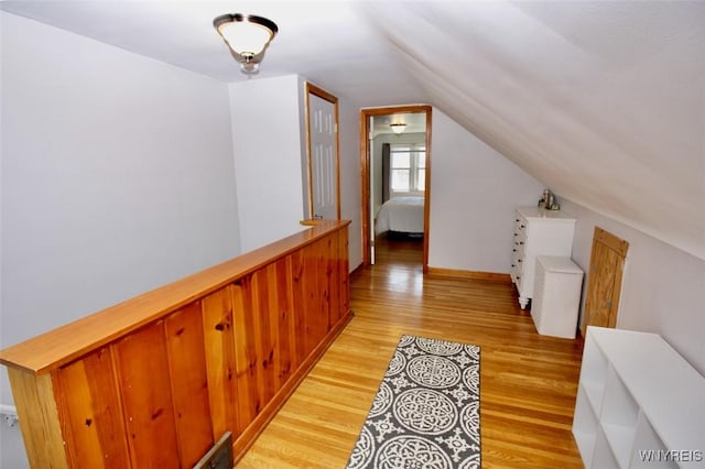 hallway with light wood-style floors and lofted ceiling