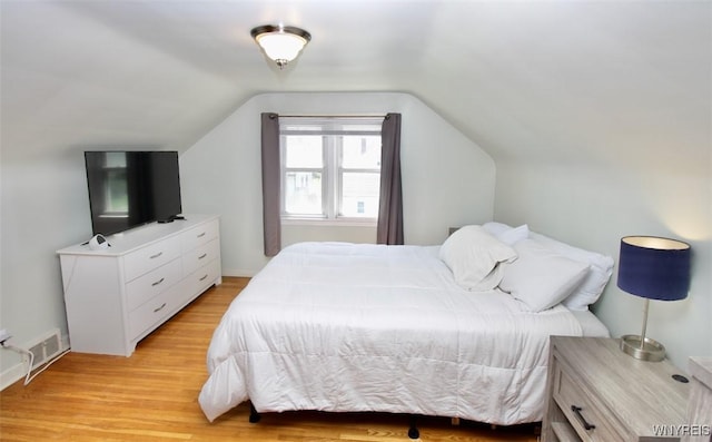 bedroom featuring vaulted ceiling, light wood finished floors, and visible vents