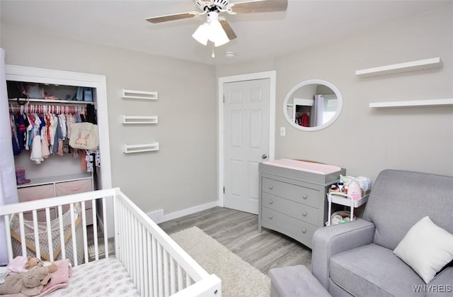 bedroom with a ceiling fan, baseboards, wood finished floors, and a closet