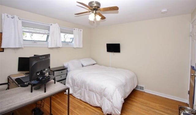 bedroom featuring baseboards, a ceiling fan, wood finished floors, and visible vents