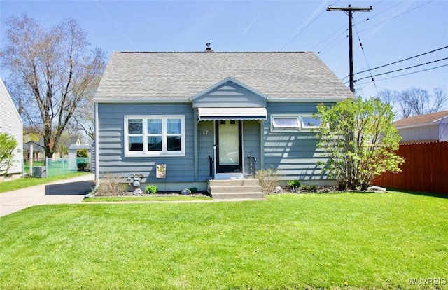 bungalow with fence, roof with shingles, driveway, and a front lawn