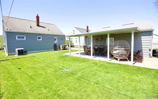 back of property with roof with shingles, central AC, a chimney, a patio area, and a yard
