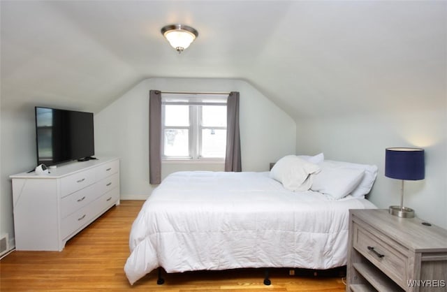 bedroom with vaulted ceiling and light wood finished floors