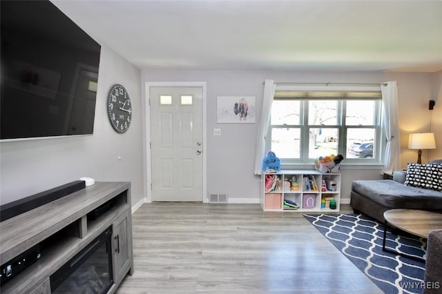 living room featuring baseboards, visible vents, and light wood finished floors