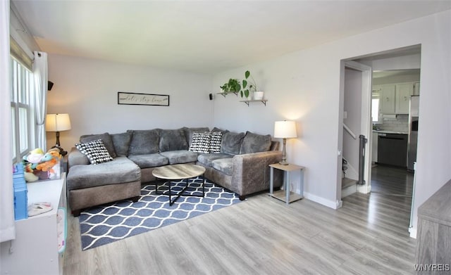 living area featuring baseboards, stairs, and wood finished floors