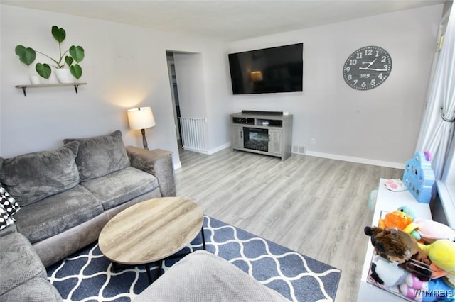 living room featuring baseboards, wood finished floors, and a fireplace