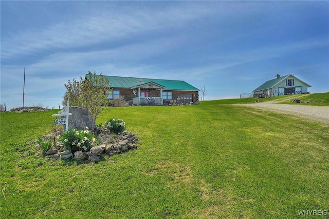 ranch-style home with driveway, metal roof, a front yard, and a garage