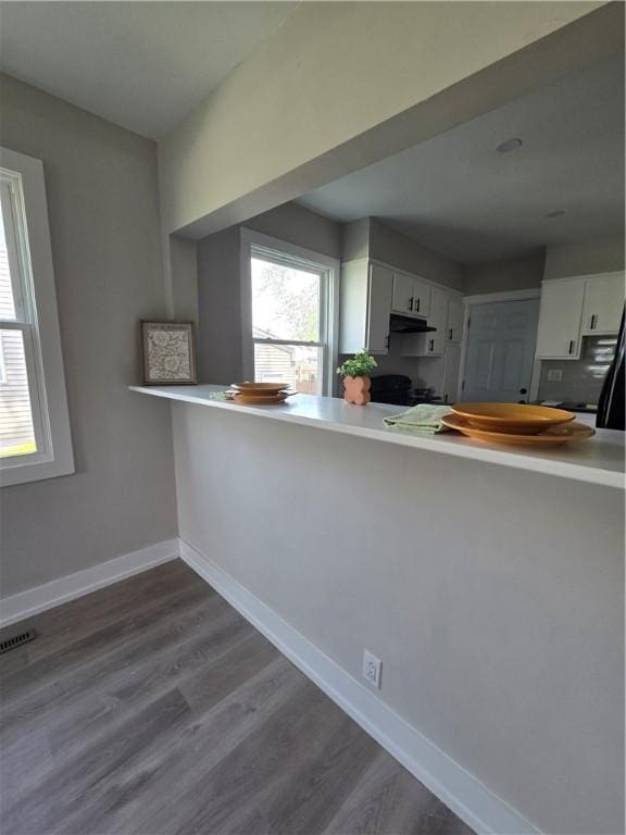 kitchen with visible vents, a peninsula, baseboards, white cabinets, and dark wood finished floors