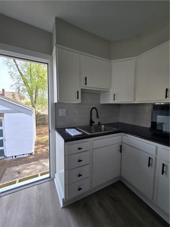 kitchen featuring a sink, dark wood-style flooring, and dark countertops