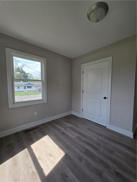 empty room with baseboards, dark wood finished floors, and visible vents
