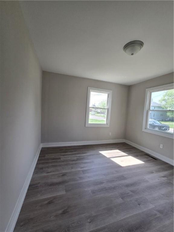 spare room featuring baseboards and dark wood-style flooring