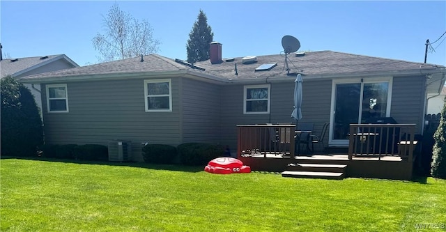 back of house with a chimney, a deck, central AC, a yard, and a shingled roof