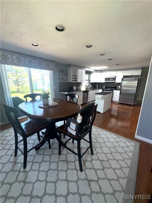 dining space with dark wood-style flooring, recessed lighting, and a textured ceiling