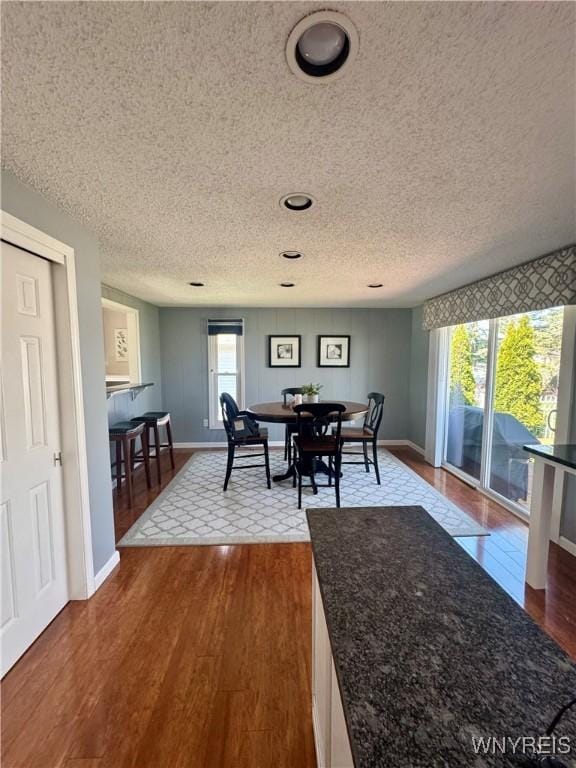 dining space featuring baseboards, dark wood-style floors, and a textured ceiling