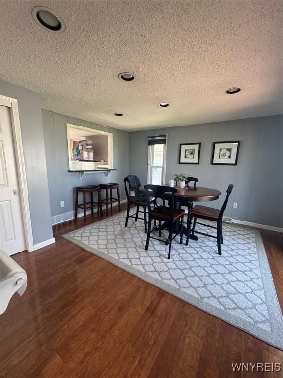 dining room featuring baseboards, a textured ceiling, and wood finished floors