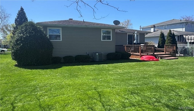 rear view of house with a lawn, a wooden deck, and central AC