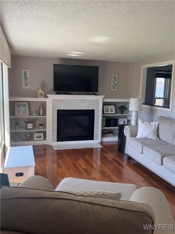 living room featuring a fireplace with flush hearth, a textured ceiling, and wood finished floors