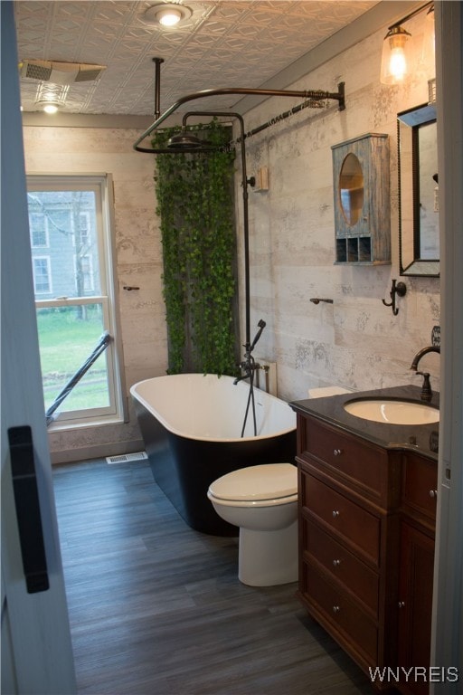 full bath with visible vents, vanity, wood finished floors, an ornate ceiling, and a freestanding bath
