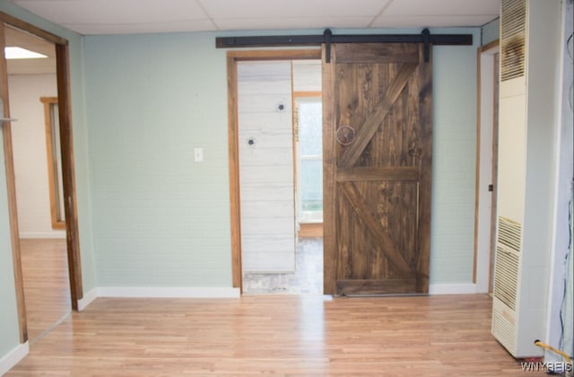 interior space with a heating unit, baseboards, and light wood-style flooring