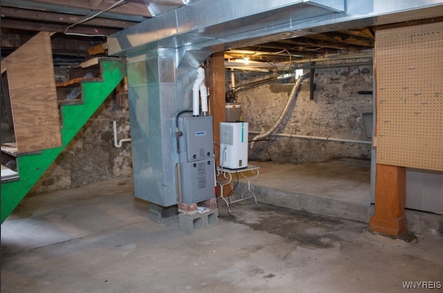 unfinished basement featuring stairs, heating unit, and water heater