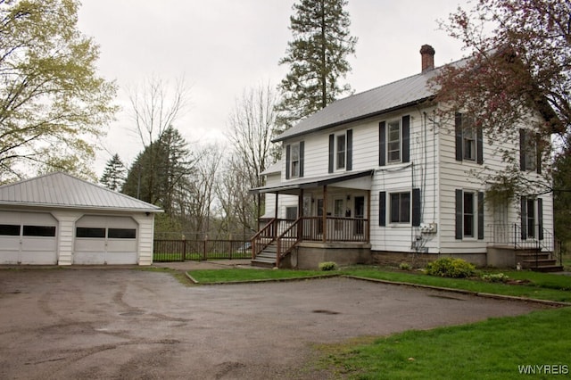 view of front of property with an outdoor structure, a garage, a chimney, metal roof, and a porch