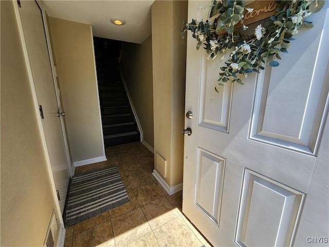 foyer with stairway, baseboards, tile patterned floors, and visible vents