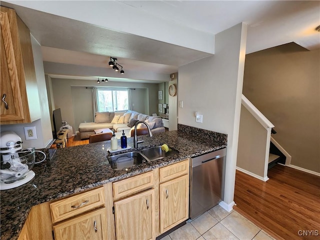 kitchen with a sink, dishwasher, dark stone counters, a peninsula, and open floor plan