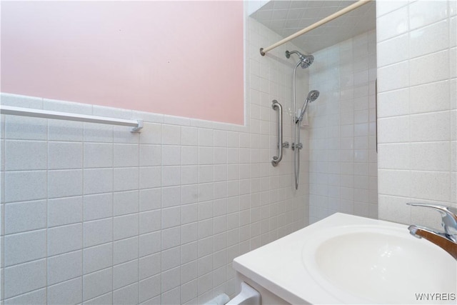 full bath with a sink, tile walls, a wainscoted wall, and walk in shower